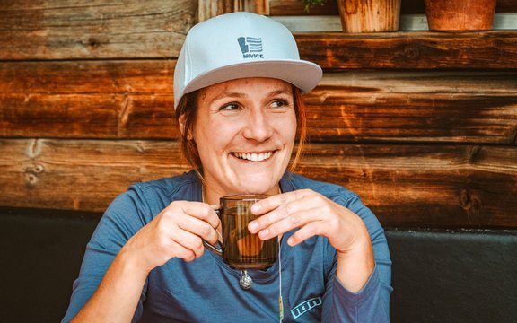 Annika Jeschke sits in front of a hut and drinks tea 