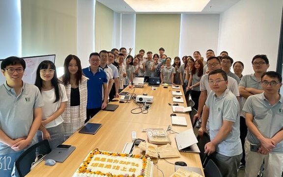 large group of employees standing around large desk looking at the camera 